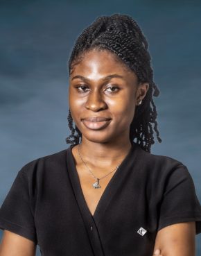 African lady in a black dress wearing a silver chain with pendant and on dreads