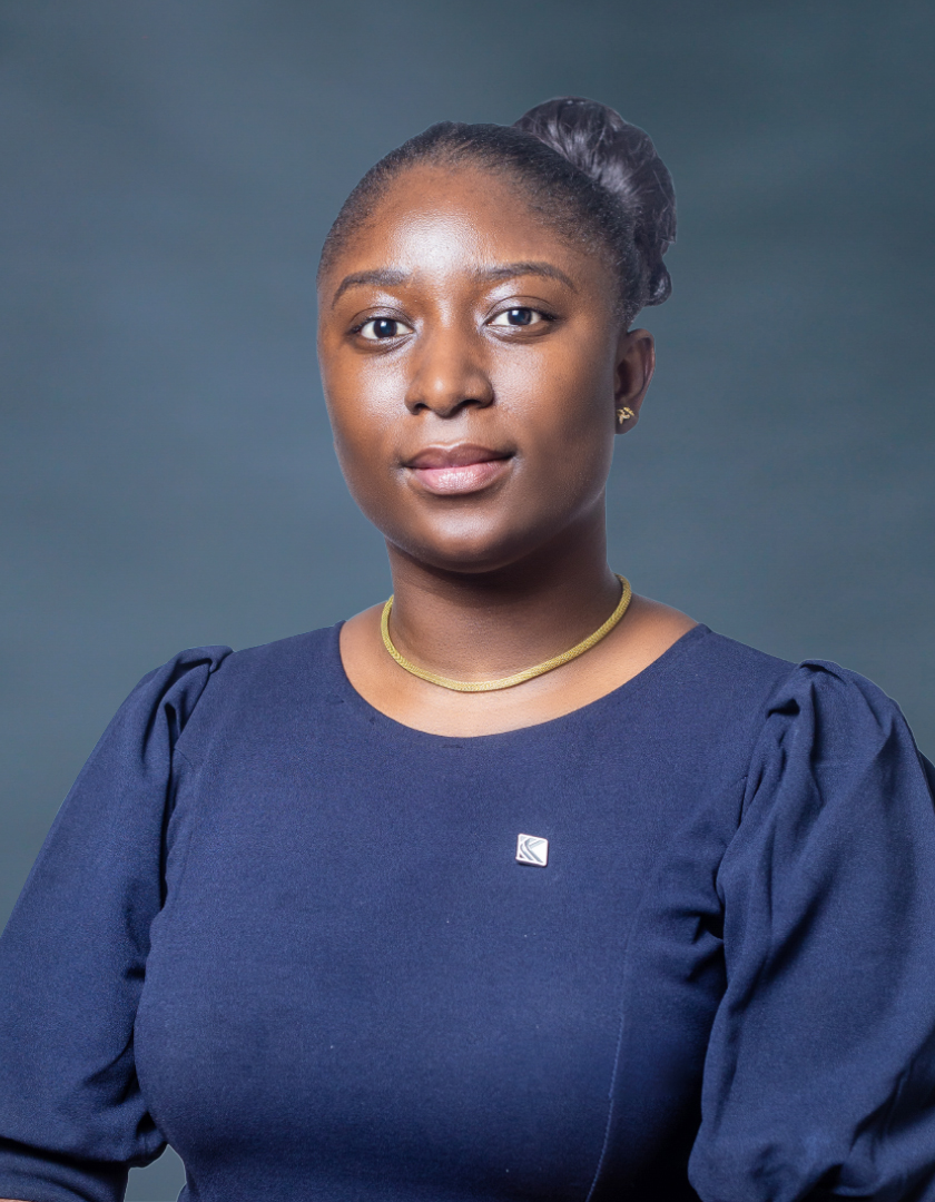 African woman in a navy blue dress, sporting a black bun and gold chain