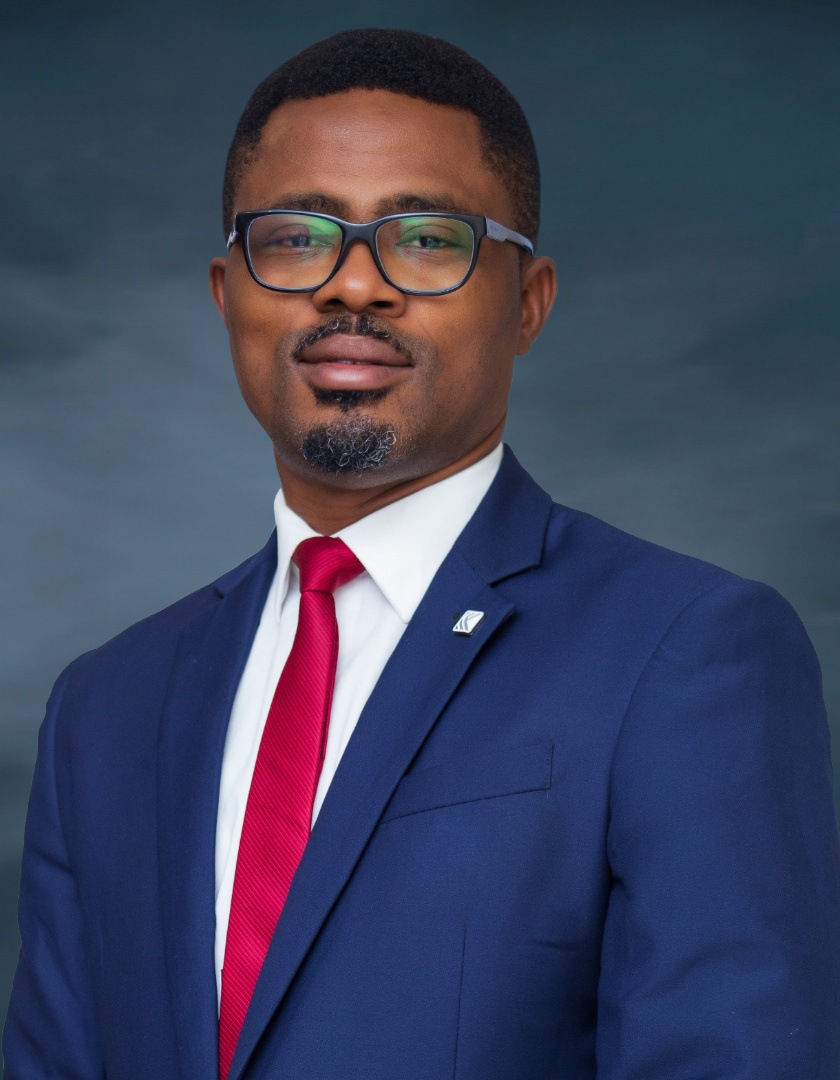 Light-skinned bespectacled African man in blue suits, white shirt and red tie