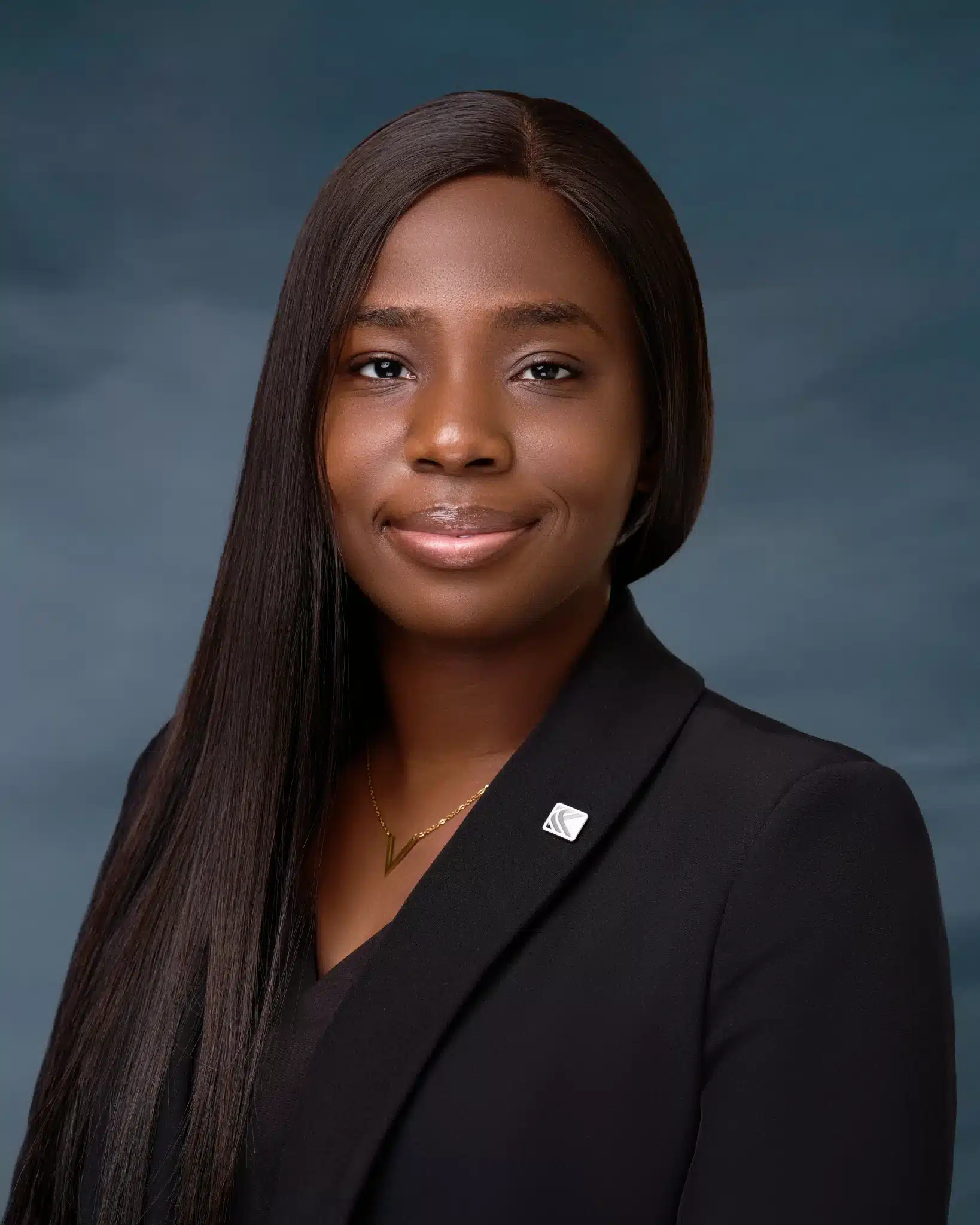 Dark skinned African woman in a black jacket sporting a long hair and a lapel pin