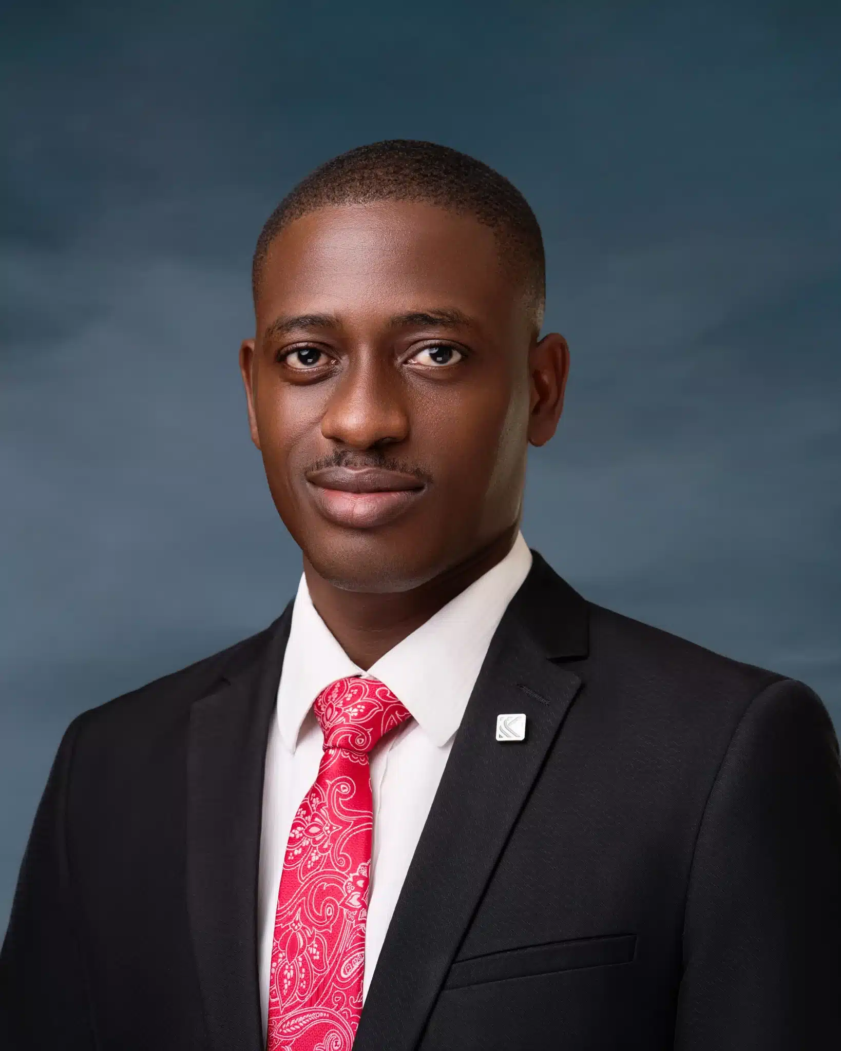 Dark-skinned African man in a black jack, white shirt and pink tie