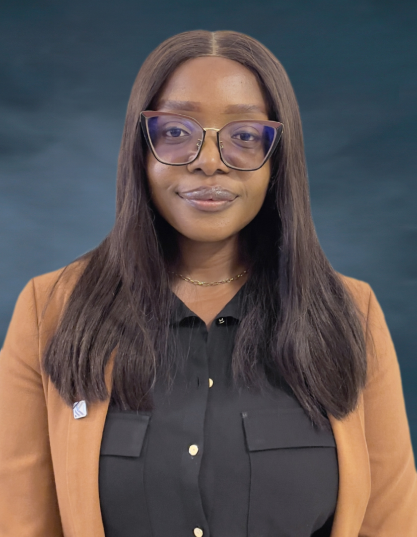 Bespectacled African woman in a long wig wearing a brown jacket and black shirt
