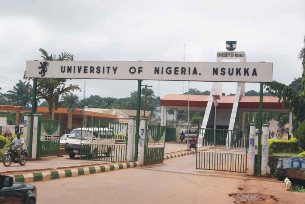 Picture of University of Nigeria gate with a white bus and a man riding a bicycle in front