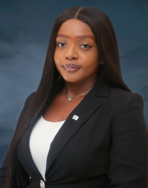 Bespectacled African woman in a long wig wearing a brown jacket and black shirt